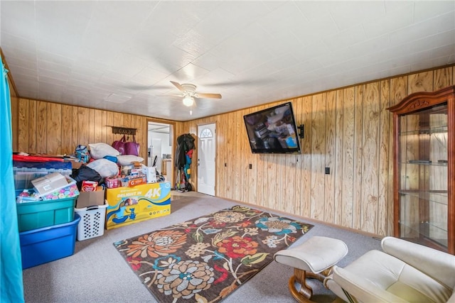 interior space featuring ceiling fan and wood walls