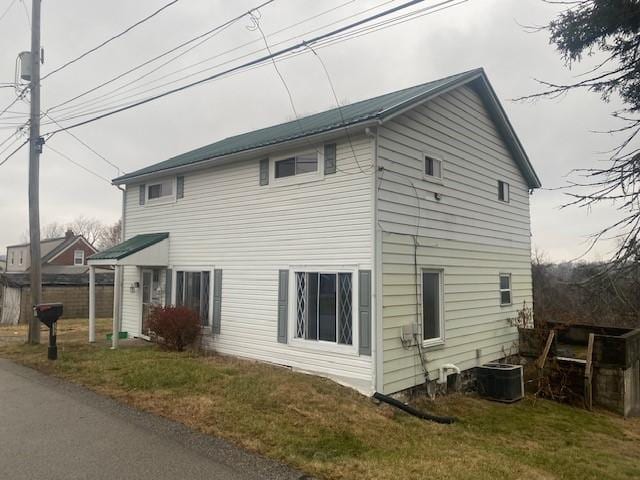 view of side of property featuring a lawn and central AC