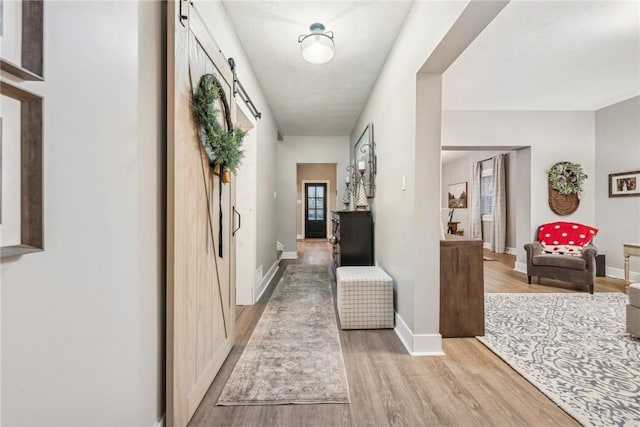 hallway featuring light wood-type flooring and a barn door