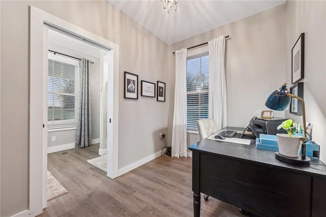 home office featuring hardwood / wood-style floors and a notable chandelier