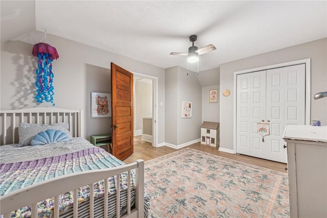 bedroom with light wood-type flooring, a closet, ceiling fan, and lofted ceiling