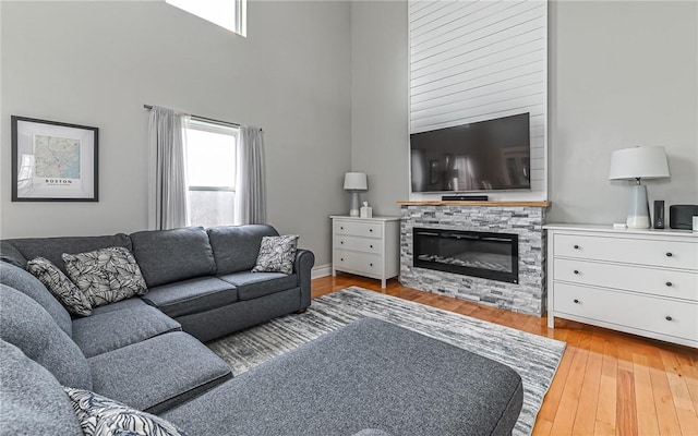 living room featuring a fireplace, a high ceiling, and light hardwood / wood-style floors