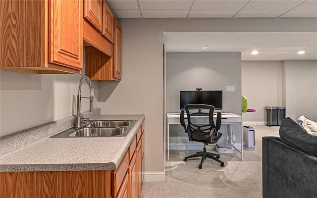 office space with a paneled ceiling, light colored carpet, and sink