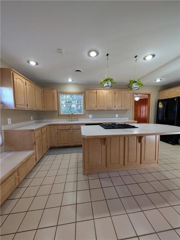 kitchen featuring light brown cabinets, a center island, black fridge, and light tile patterned flooring