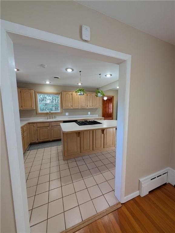 kitchen featuring light brown cabinets, light wood-type flooring, hanging light fixtures, and a baseboard heating unit