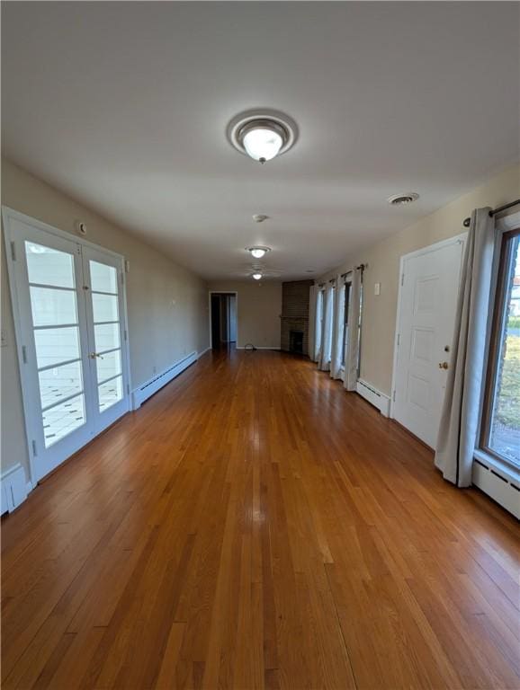 empty room featuring wood-type flooring and baseboard heating