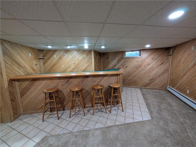 bar with tile patterned floors, wood walls, and a baseboard heating unit