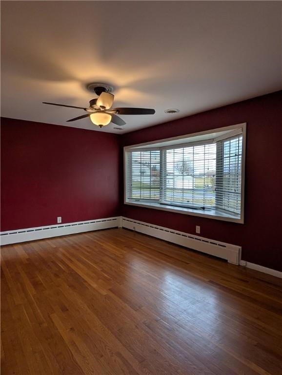 unfurnished room with ceiling fan, wood-type flooring, and a baseboard heating unit