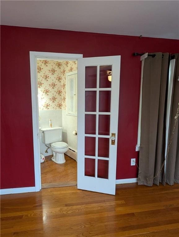 bathroom featuring hardwood / wood-style floors, toilet, french doors, and a baseboard heating unit