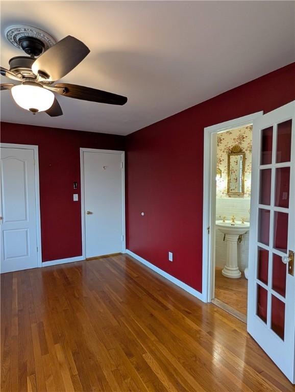 unfurnished bedroom featuring ensuite bath, ceiling fan, hardwood / wood-style floors, and french doors