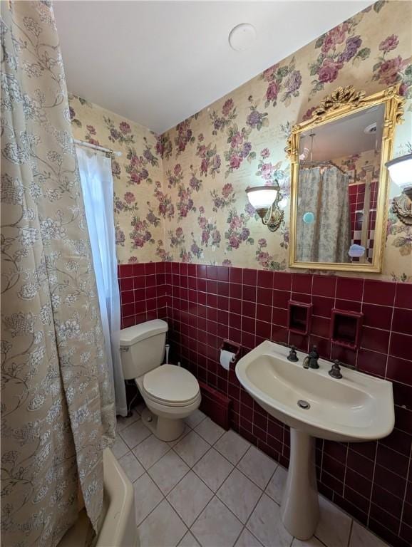 bathroom featuring shower / bath combo with shower curtain, tile patterned flooring, tile walls, and toilet