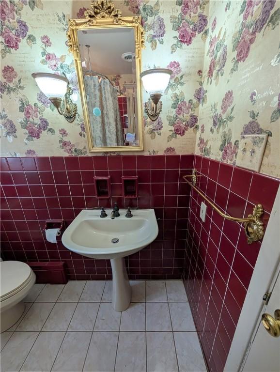 bathroom featuring tile patterned floors, sink, tile walls, and toilet