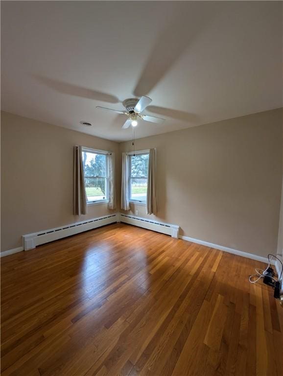 unfurnished room featuring hardwood / wood-style flooring, baseboard heating, and ceiling fan