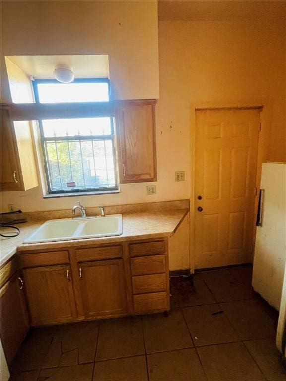 kitchen featuring white fridge, dark tile patterned flooring, and sink