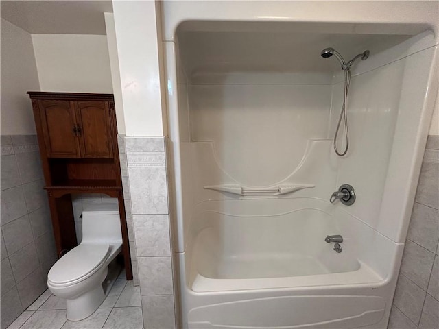 bathroom with tile patterned floors, toilet, tile walls, and shower / washtub combination