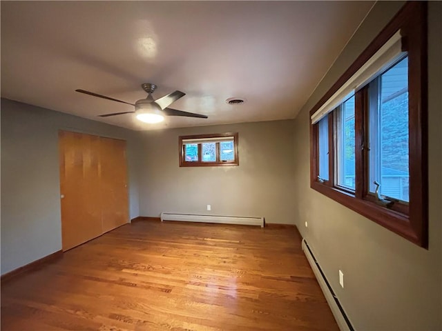 unfurnished bedroom featuring a closet, ceiling fan, hardwood / wood-style floors, and a baseboard radiator