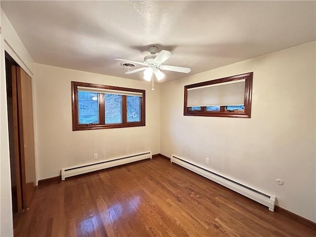 unfurnished bedroom with ceiling fan, a closet, dark hardwood / wood-style flooring, and a baseboard heating unit