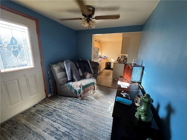 living area featuring carpet flooring and ceiling fan