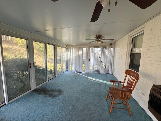 unfurnished sunroom featuring heating unit and ceiling fan