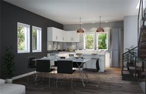 kitchen with a breakfast bar area, decorative light fixtures, a center island, dark hardwood / wood-style flooring, and white cabinets