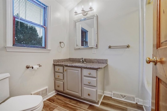 bathroom with hardwood / wood-style floors, vanity, lofted ceiling, and toilet