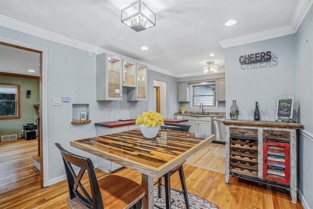 kitchen featuring light hardwood / wood-style floors, stainless steel dishwasher, crown molding, and sink