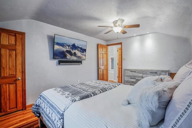 bedroom with a textured ceiling, light hardwood / wood-style flooring, vaulted ceiling, and ceiling fan