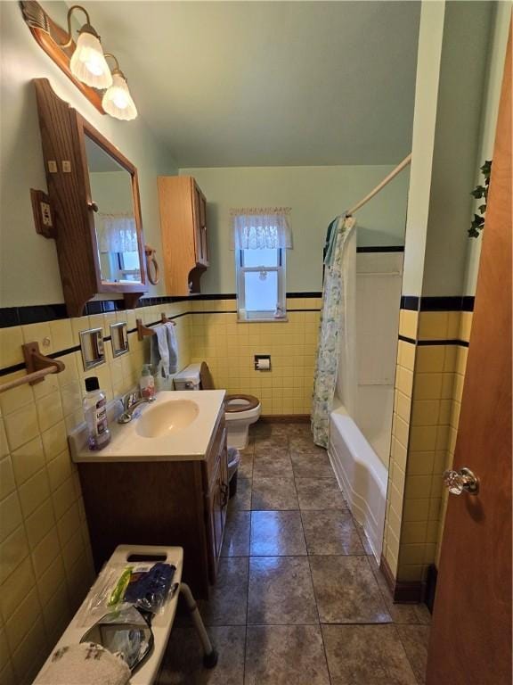 full bathroom featuring shower / bathtub combination with curtain, tile patterned flooring, toilet, vanity, and tile walls