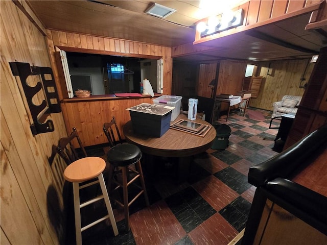 dining room featuring wood walls and bar area