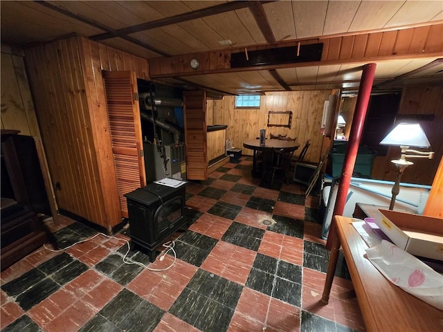 basement featuring wooden ceiling, a wood stove, and wooden walls