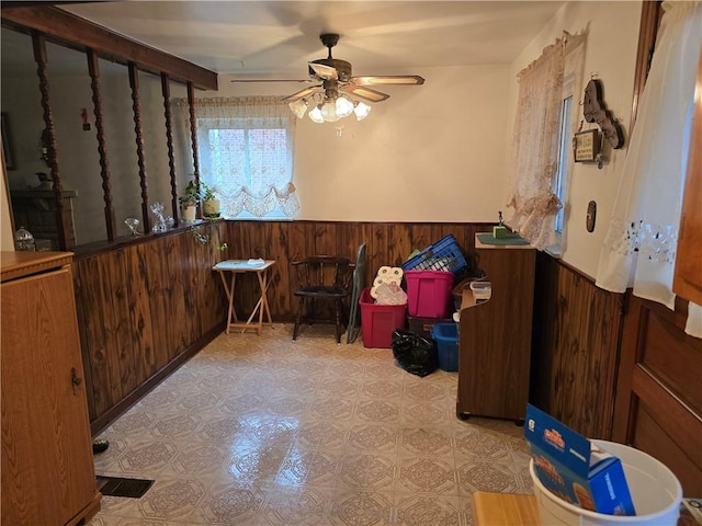 interior space with ceiling fan and wooden walls