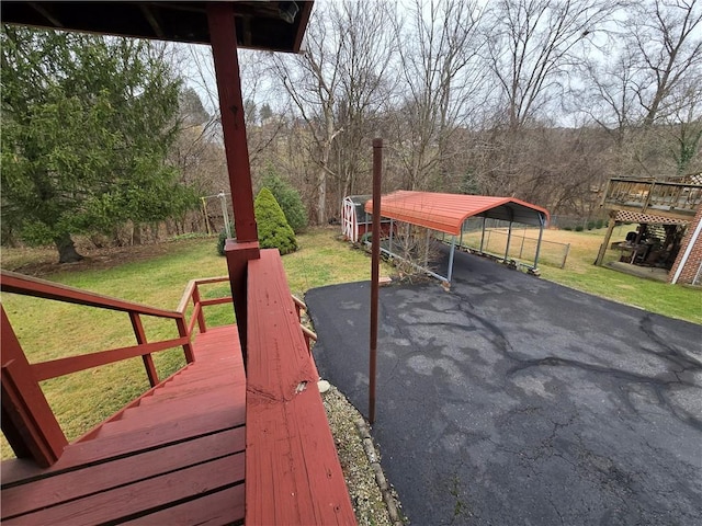 wooden deck featuring a lawn and a carport