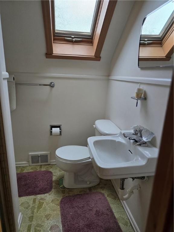 bathroom with a skylight, sink, and toilet