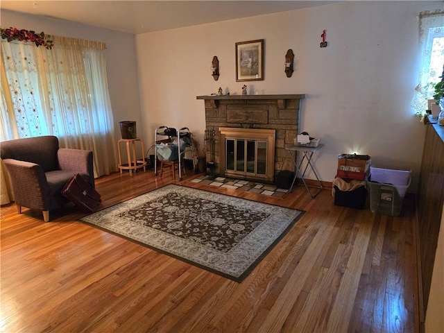 living area with hardwood / wood-style floors and a stone fireplace