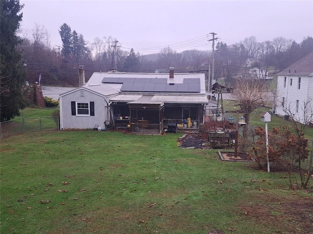 rear view of property with solar panels and a yard