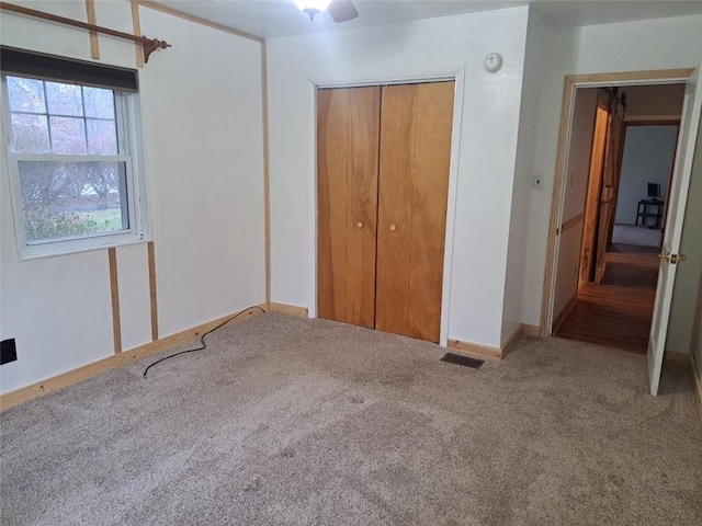 unfurnished bedroom with carpet flooring, ceiling fan, and a closet