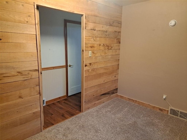 empty room with wooden walls and dark colored carpet