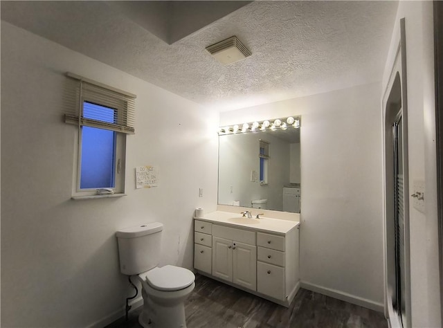 bathroom featuring an enclosed shower, vanity, a textured ceiling, hardwood / wood-style flooring, and toilet