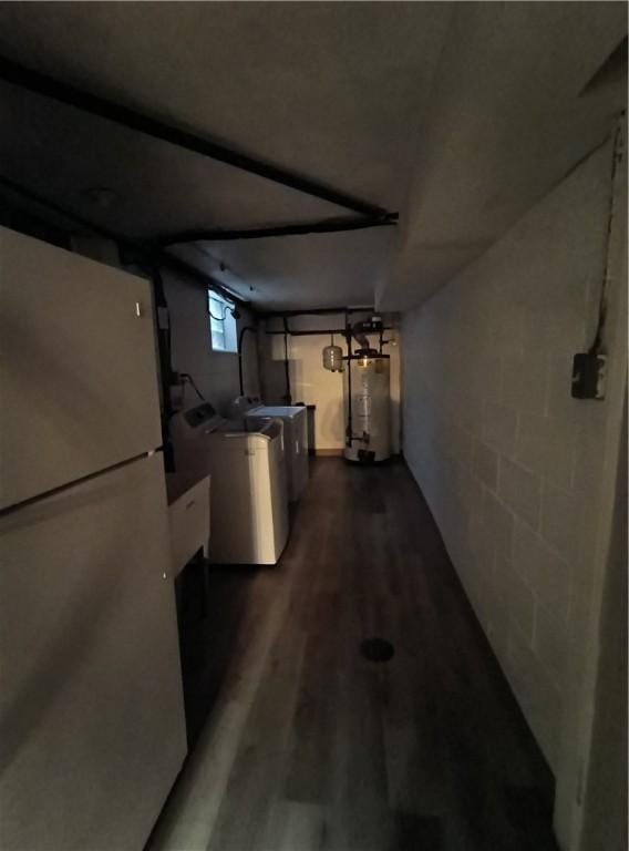 basement featuring washing machine and dryer, gas water heater, dark hardwood / wood-style floors, and fridge