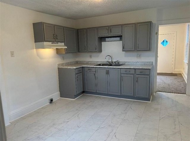 kitchen with a textured ceiling, gray cabinetry, and sink