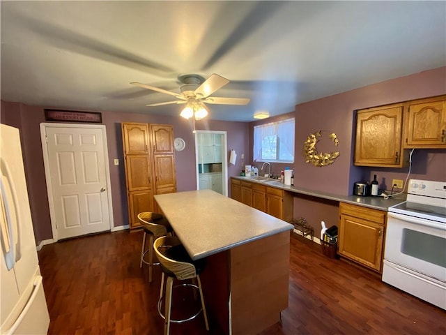 kitchen with dark hardwood / wood-style floors, white appliances, sink, and a breakfast bar area