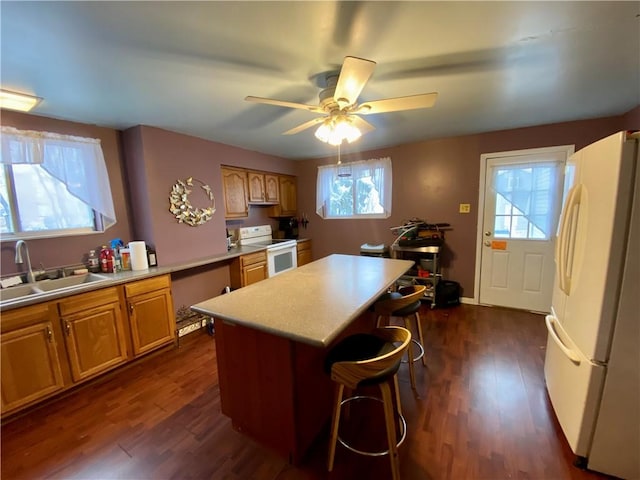 kitchen with a wealth of natural light, sink, dark hardwood / wood-style floors, and white appliances