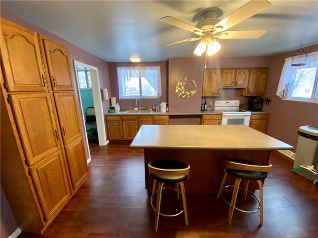 kitchen with a kitchen bar, electric stove, sink, and a kitchen island