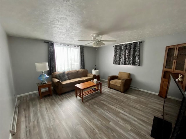 living room featuring hardwood / wood-style floors, ceiling fan, a textured ceiling, and a baseboard heating unit