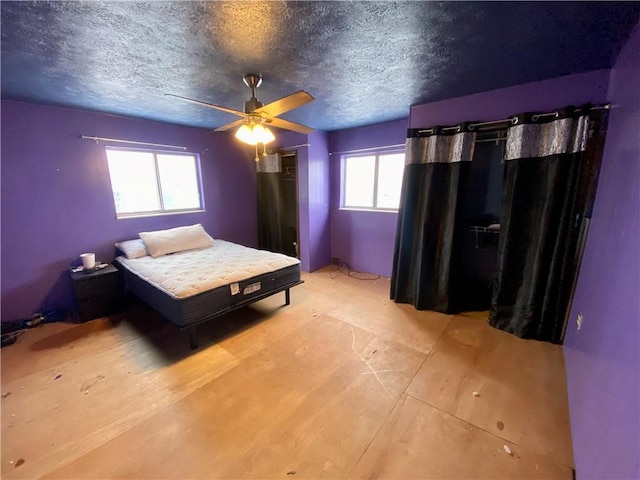 unfurnished bedroom featuring a textured ceiling, multiple windows, and ceiling fan