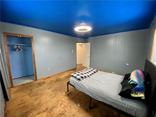 bedroom featuring wood-type flooring, wooden walls, and a closet