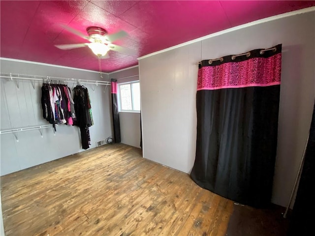 unfurnished bedroom featuring ceiling fan, wood-type flooring, and a closet