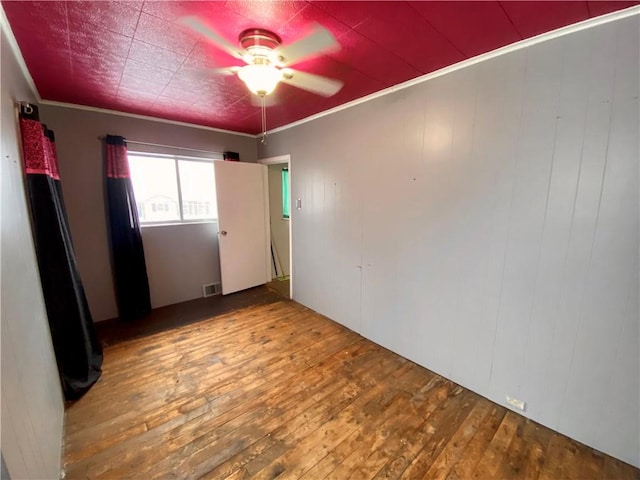 empty room featuring ceiling fan, wood-type flooring, and ornamental molding