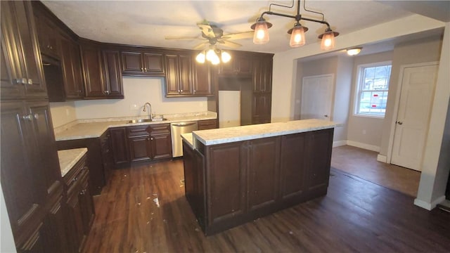 kitchen featuring dishwasher, sink, decorative light fixtures, a kitchen island, and dark hardwood / wood-style flooring