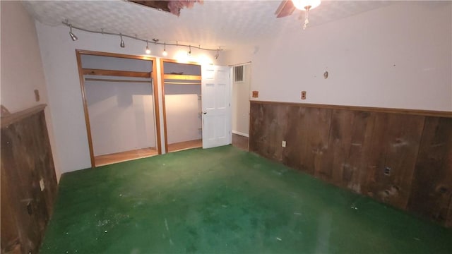 unfurnished bedroom featuring ceiling fan, concrete flooring, and wooden walls